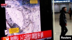 一名旅客2013年2月12日在首尔的一个火车站经过一个正在播放朝鲜核试验的电视看版。