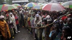 Internally displaced Congolese men and women wait for a World Food Program energy biscuits to be distributed in Kibati, north of Goma, eastern DRC, August 8, 2012.