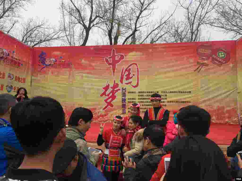 在北京地坛公园春节庙会上，在《中国梦》看板前，台湾原住民装扮的青年男女和游客合影（2016年2月8日， 美国之音叶兵拍摄 ）