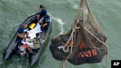 印尼救援人員從水中打撈出巨型物體。