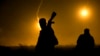 FILE - A U.S.-backed Syrian Democratic Forces (SDF) fighter watches illumination rounds light up Baghuz, Syria, as the last pocket of Islamic State militants is attacked on March 12, 2019. 