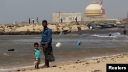 一名男子与他的儿子站在印度南部泰米尔纳德邦的库丹库拉姆核电站附近(资料照片)