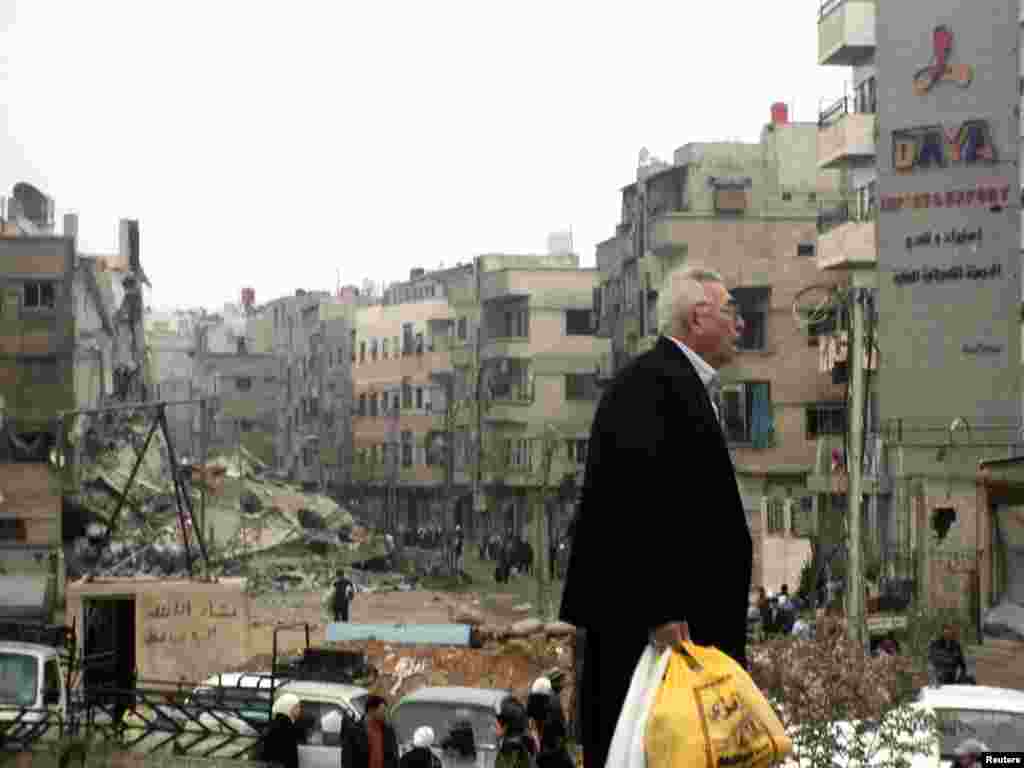 Residents walk near buildings damaged after shelling by forces loyal to Syria's President Bashar al-Assad, near Damascus, November 19, 2012.