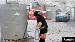 2013年12月11日，在黎巴嫩的貝卡山谷難民營的敘利亞難民在嚴冬下接水的情況。