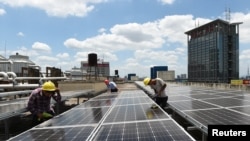 工人在中国浙江省义乌市义乌国际商贸城屋顶安装太阳能电池板。（2017年7月17日）