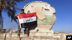 Иракский солдат c национальным флагом на вершине правительственного комплекса в центре Рамади. Ирак, 28 декабря 2015.