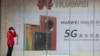 疫情期间一名妇女站在位于北京的华为手机5G广告旁。（2020年3月8日）