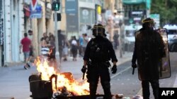 Polisi wa kuzuia ghasia karibu na moto uliyowashwa na waandamanaji mjini Paris, Jumamosi.