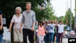 在发生袭击的现场，被疏散的人们举起双手走出购物中心（2016年7月22日）