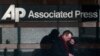 A man looks down at his smartphone as he walks past the offices of the Associated Press in Manhattan, New York, May 13, 2013.
