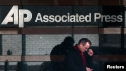 A man looks down at his smartphone as he walks past the offices of the Associated Press in Manhattan, New York, May 13, 2013.