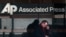 A man looks down at his smartphone as he walks past the offices of the Associated Press in Manhattan, New York, May 13, 2013.