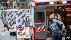 A patient arrives in an ambulance cared for by medical workers wearing personal protective equipment due to COVID-19 concerns outside NYU Langone Medical Center in New York, April 13, 2020.