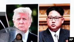 在东京，一位女士走过显示美国总统川普和朝鲜领导人金正恩的巨大屏幕。（2018年3月9日）