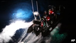 2014年2月23日在南极海，海洋守护者协会的一个橡皮艇上的活动人士试图用绳子套住一只日本捕鲸船