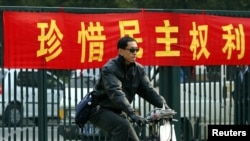 資料照：一名男子在北京街頭騎車路過一條敦促市民”珍惜民主權利“的標語橫幅。（2003年11月4日）