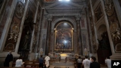 People wearing face masks to prevent the spread of COVID-19 pray in John Paul II chapel in St. Peter's Basilica at the Vatican in the day of its reopening which coincided with John Paul II 100th anniversary of birth, May 18, 2020. 