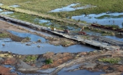 FILE - An aerial photo shows the devastation caused by Cyclone Idai as local residents walk on a damaged road in Beira, Mozambique, March 23, 2019.