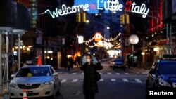 一名戴着口罩和手套的女子在曼哈顿街上行走。（2020年3月18日）