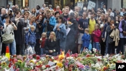 人们在奥斯陆教堂前纪念遇难者的花海前面驻足