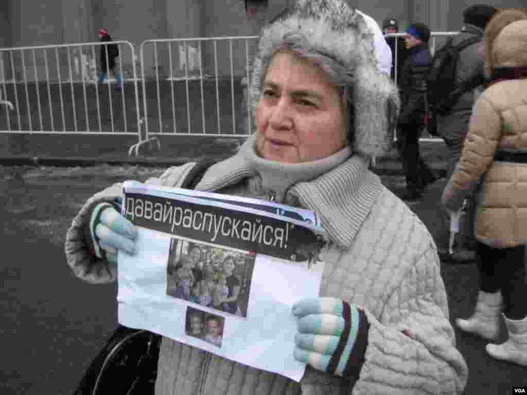 一名莫斯科示威者用照片展示美国父母和他们从俄罗斯领养的儿童。(美国之音白桦拍摄)