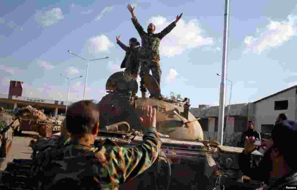 Syrian fighters celebrate the victory on top of a tank they took after storming a military base in Aleppo, November 19, 2012.