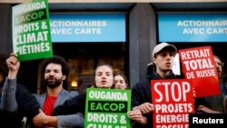 Wanaharakati wa mazingira wameshikilia mabango yakipinga mradi wa nishati wa Uganda wakati wa maandamano ya kuingilia kati mkutano wa wanahisa wa TotalEnergies, Paris, Ufaransa, Mei 25, 2022. REUTERS