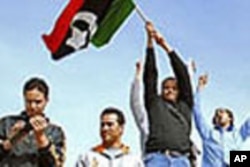 Wasu 'yan kasar Libiya masu zanga-zanga rike da tuta a kan wani tankin yaki a garin Benghazi.