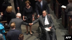 2018年4月21日，在美国德克萨斯州休斯顿的圣马丁主教教堂，前总统老布什参加芭芭拉·布什的葬礼后，前总统小布什推着坐在轮椅上的父亲离开会场。