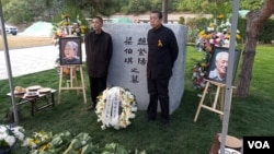 2019年10月18日，趙紫陽夫婦墓碑前擺放著出席骨灰安葬儀式的親友們獻的鮮花。趙紫陽之子趙二軍（右）立於碑前。（美國之音艾倫拍攝）