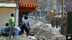 乌鲁木齐市的维吾尔人在自己的居住区附近观望值勤的武警(资料照片)