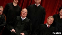 FILE - U.S. Supreme Court Justice Anthony Kennedy (L) reacts while chatting with Chief Justice John Roberts (R) during a new U.S. Supreme Court family photo.