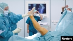 FILE - Doctors and medical staff work during knee prosthesis surgery in an operation room at the hospital of the Canton of Nidwalden in Stans, Switzerland, Oct. 27, 2011.