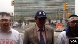 王炳章的弟弟王炳武（左）、中國民主黨全國委員會共同主席王軍濤和黨員楊維鋒在紐約聯合國大樓前淋雨請願。（美國之音方方拍攝）