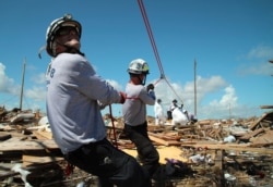 Members of the fire rescue team Task Force 8, from Gainesville, Florida, help remove a body one week after Hurricane Dorian hit Abaco Island, Bahamas, Sept. 9, 2019.