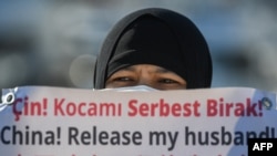 一名維吾爾婦女在中國駐伊斯坦布爾領事館附近舉牌抗議，要求中國政府釋放其丈夫。（2021年2月22日）