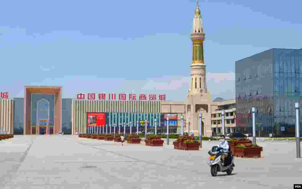 一名妇女开摩托车经过空旷的银川国际贸易中心前的广场，这个贸易中心是为了开发该地区与伊斯兰教有关产品的贸易。