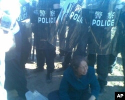 一个巴林左旗妇人无力奔跑，坐在警察的包围圈中