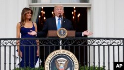 President Donald Trump, with first lady Melania Trump, speaks from the Truman Balcony at the Fourth of July picnic for military families on the South Lawn of the White House, Tuesday, July 4, 2017.