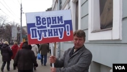 俄羅斯吞併克里米亞後，當局去年3月在莫斯科組織親政府支持普京集會遊行。普京的一名支持者手舉標語：我們信任普京。（美國之音白樺拍攝）