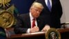 FILE - President Donald Trump signs an executive order to impose tighter vetting of travelers entering the United States, at the Pentagon in Washington, Jan. 27, 2017. 