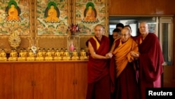 西藏精神領袖達賴喇嘛在印度達蘭薩拉的住所內在僧侶的扶助下步入大廳。 （2024年12月20日）