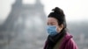 巴黎市埃菲尔铁塔前一名女子戴上口罩（路透社2020年1月25日）