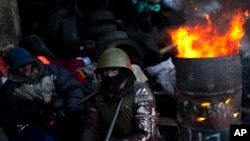 反对派的支持者1月31日在基辅独立广场附近的障碍物旁烤火。