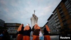 2025年3月8日，羅馬傑梅利醫院外，修女聚集在臨時紀念碑附近，教宗方濟各正在那裡接受雙肺炎治療。