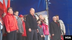 共产党议员卡申（身穿红衣）同俄共领袖久加诺夫（讲话者）在5月1日莫斯科共产党游行集会上（美国之音白桦拍摄）