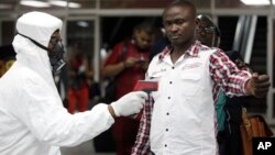 2014年8月6日一名尼日利亞港口檢疫人員為一名在拉各斯入境的旅客測量體溫。