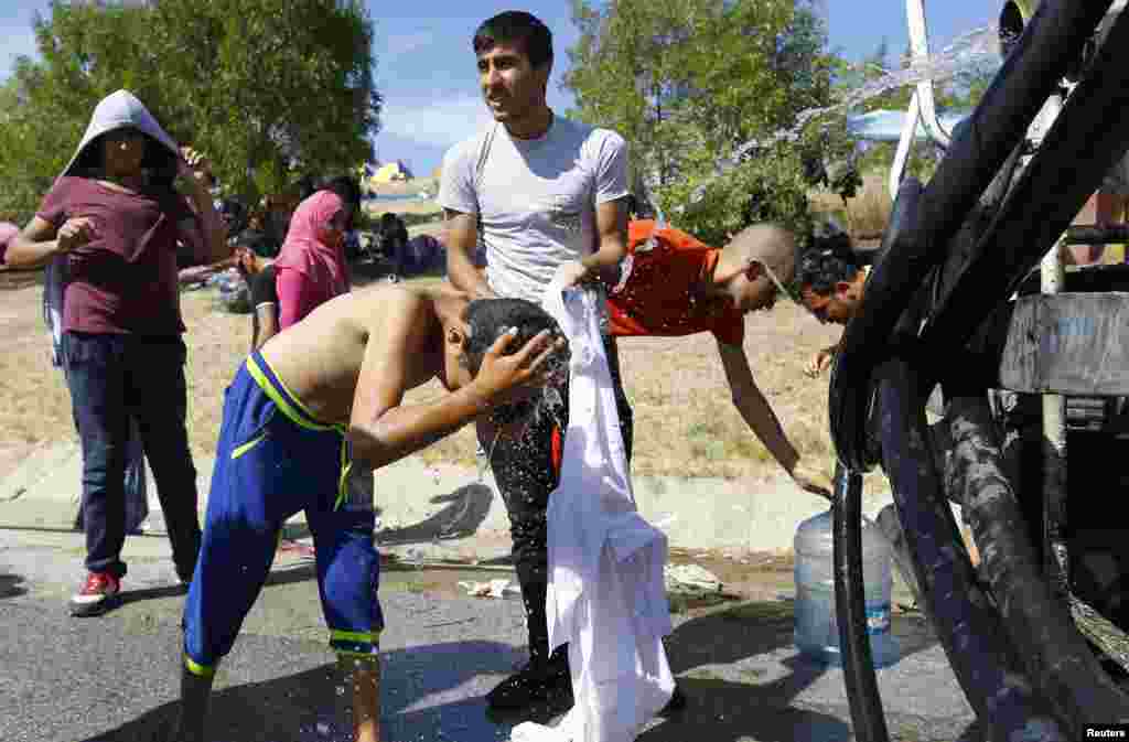 A migrant child washes his head with water on the side of a highway near Edirne, Turkey. Hundreds of migrants spent the night out in the open near Turkey&#39;s border with Greece, after Turkish police halted their bid to reach the frontier and cross into the European Union.