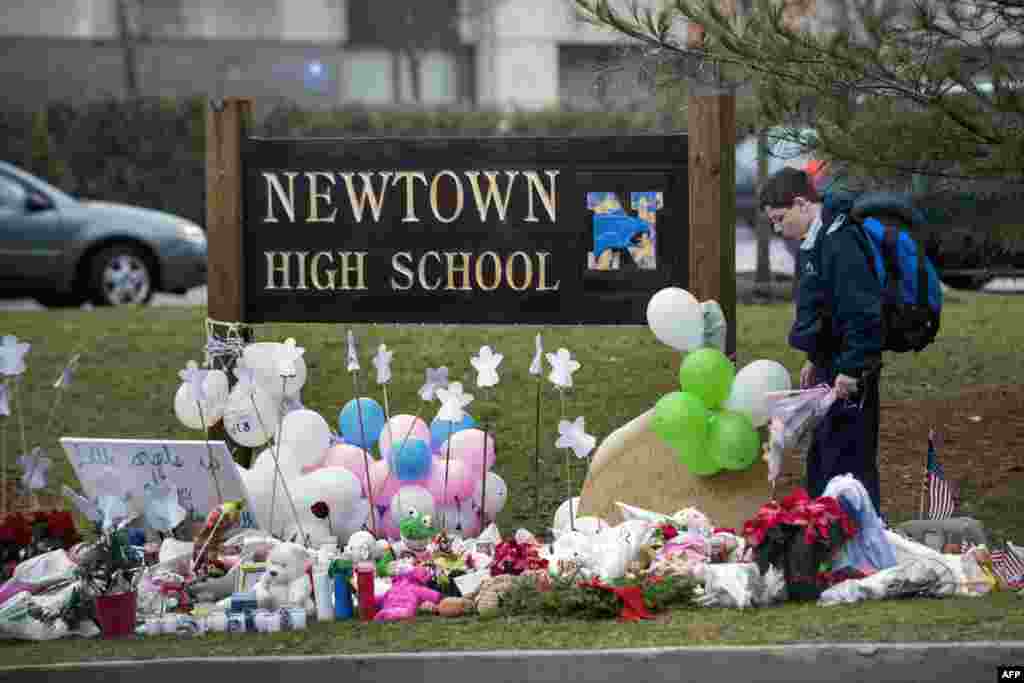 A student looks for a place to leave flowers at a makeshift memorial for the victims of the Sandy Hook Elementary School shooting at the entrance of Newtown High School December 18, 2012 in Newtown, Connecticut.