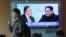 一名韩国军人从首尔火车站播报显示蓬佩奥和金正恩图像的新闻节目的电视屏幕前走过。（2018年4月18日）
